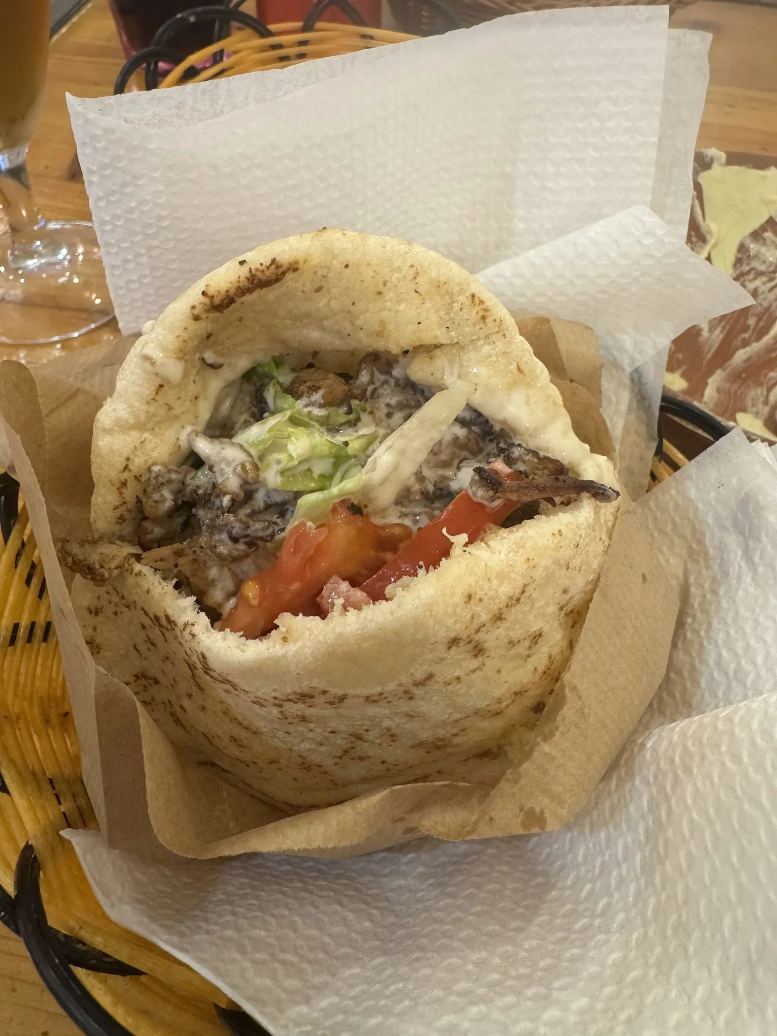 Pita de shawarma oberta, amb carn, enciam, tomàquet i salsa blanca, en una cistella